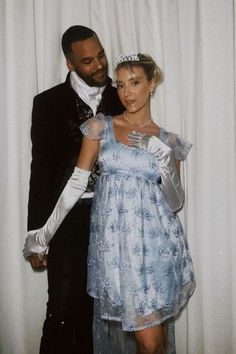 a man in a tuxedo standing next to a woman wearing a blue dress