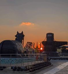 the sun is setting behind two large statues in front of a building with an elephant on it