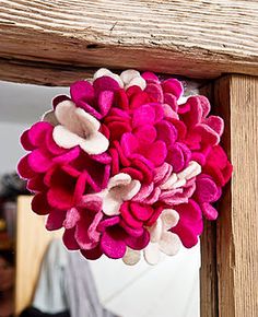 a pink and white flower is hanging on the side of a wooden frame with a mirror in the background