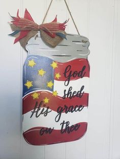 a patriotic sign hanging from the side of a white door that says god shed his grace on thee