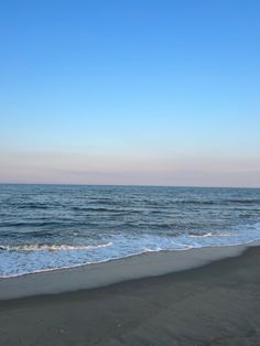 the beach is empty and blue with waves coming in