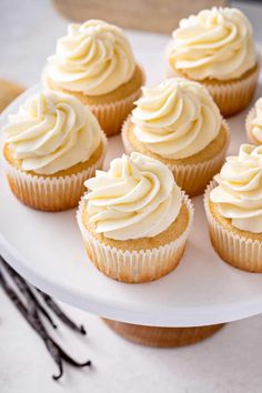 cupcakes with white frosting sitting on a cake plate