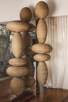 a sculpture made out of wicker stacked on top of each other in front of a window