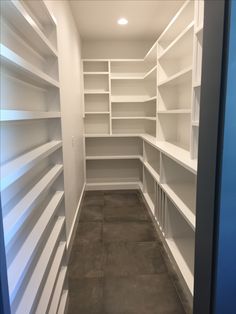 an empty walk in closet with white shelving