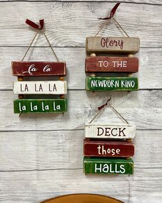 three wooden signs hanging on the side of a white wood wall with red and green lettering