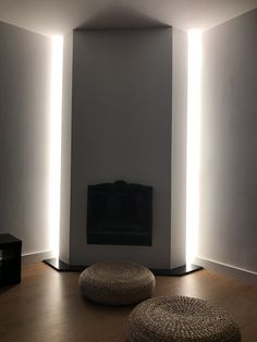 two round ottomans sit in front of a flat screen tv on a wall with lights