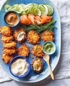 a blue plate topped with different types of food next to cucumbers and dips