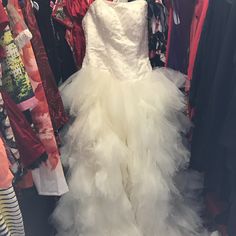 a wedding dress hanging on a rack in a clothing store with other dresses behind it