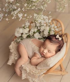 a baby sleeping in a wooden chair next to flowers