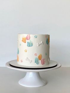 a white cake with colorful dog paw prints on it sitting on top of a plate