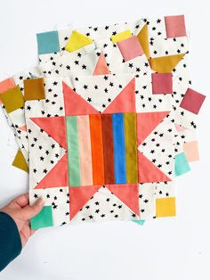 someone is holding up some colorful pieces of fabric to make a star shaped wall hanging