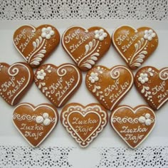 twelve heart shaped cookies decorated with white icing on a lace doily tablecloth