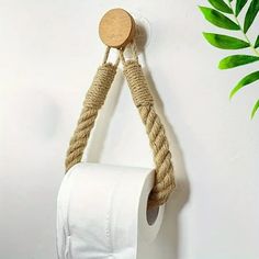 a roll of toilet paper hanging from a rope with a wooden button on the end