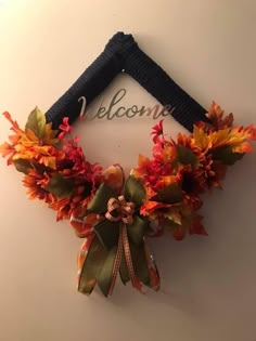 a welcome sign hanging from the side of a wall decorated with fall leaves and ribbons