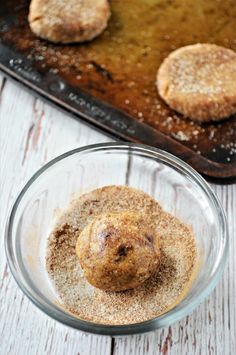 some food is in a glass bowl on a table next to a baking pan with cookies