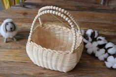 a small basket with cotton in front of it on a table next to a toy sheep