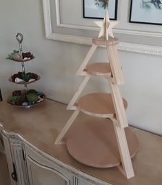 a wooden christmas tree sitting on top of a table next to a white framed picture