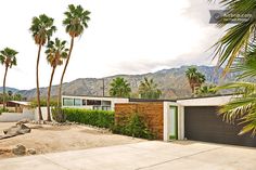 a house with palm trees and mountains in the background