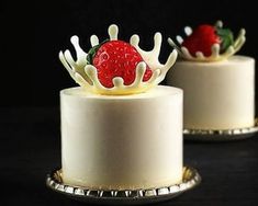 two small cakes with white frosting and strawberries on top, one is red