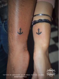 two people holding hands with tattoos on their arms and one has an anchor tattoo on the other arm