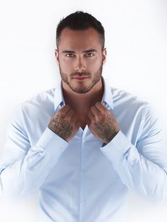 a man with tattoos on his arms and chest posing for a photo in front of a white background