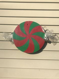 a red and green peppermink candy cane on top of a white house wall