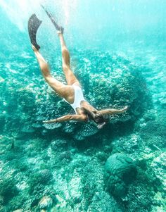 a woman swimming in the ocean with her legs spread out and feet up above water's surface