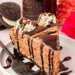 a slice of chocolate cheesecake on a white plate with oreo cookies in the background