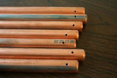 six copper pipes lined up on a wooden table