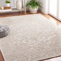 a white rug with an intricate design on the floor in front of a potted plant