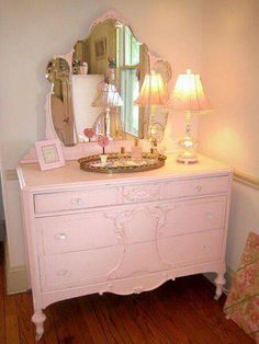 a pink dresser with a mirror and lamp on top