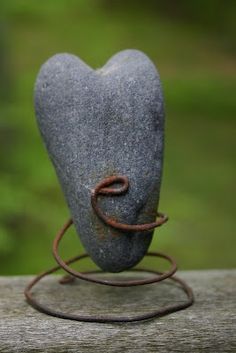 a heart shaped rock sitting on top of a wooden table next to a metal wire