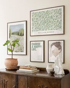 there are pictures hanging on the wall next to a dresser with books and a potted plant