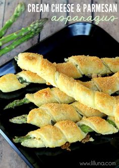 cream cheese and parmesan appetizers on a black plate with asparagus