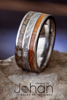 a wedding band with wood and silver inlays on top of a rock,