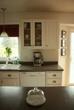 a kitchen with white cabinets and black counter tops in front of an open glass door