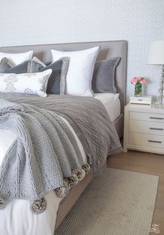 a bedroom with a bed, nightstands and pillows on the side table in front of it