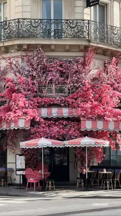 an outdoor cafe with pink flowers on the outside