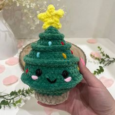 a hand holding a small green crocheted christmas tree cupcake