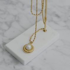 "A feminine and Parisian styled necklace, designed with twist details. Beautiful gold finish. This necklace is a perfect statement for your daily outfits. - Materials: 18K gold plated titanium and acrylic pearl - Measurements: the charm is approximately 0.85\" / 2.2cm in diameter - Length: approximately 18\" / 46cm in total length with 2\" / 5cm extension - The product is tarnish-resistant and hypoallergenic Q&A 1. What is the material? - It is made from 18K real gold plated titanium. Titani Elegant Necklace With Rope Chain And Round Pendant, Elegant Rope Chain Necklace With Round Pendant, Pearl Charm Necklace, Stacked Necklaces, Hypoallergenic Jewelry, Gold Snake, Rope Necklace, Pearl Pendant Necklace, Pearl Charms