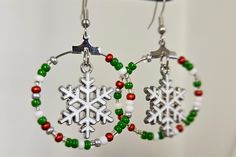 Snowflake Hoop Earrings are adorable for ringing in the holidays! Show your holiday spirit with these winter beaded earrings.  Red, white, clear, silver and green seed beads adorn these medium hoops and frame cute silver and white snowflake charms. These Christmas earrings are sure to turn some heads. Nickel-free, silver colored ear wires. Snowflake earrings hoops measure about 2" long. Fun and flirty, these seed bead earrings are perfect for holiday parties, Christmas, New Year's eve, work parties, work, shopping, night out with the girls, concerts and more.  These hoop earrings for women also make a great gift for her, gift for mom, gift for friend, gift for sister, gift for teen, Christmas gift, unique stocking stuffer and more. Handmade in the USA, shipped from the United States. All o Handmade Snowflake Jewelry For Christmas, Handmade Snowflake Jewelry For Holiday, Teen Christmas Gift, Christmas Beading, Snowflake Jewelry, Work Parties