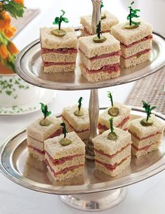 several small sandwiches on a silver platter with toothpicks sticking out of them