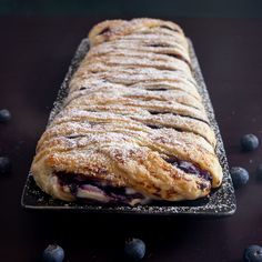 blueberry croissant with powdered sugar on top sitting on a black surface