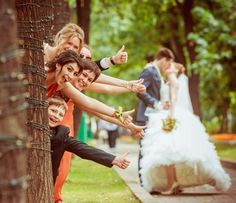 a group of people standing next to each other on top of a tree trunk with their hands in the air