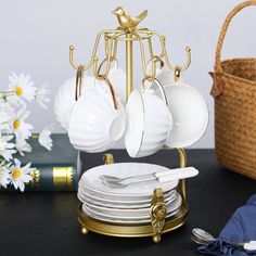 a stack of white plates sitting on top of a table next to a basket filled with flowers