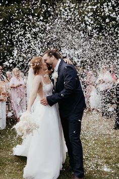 a newly married couple kissing in front of confetti