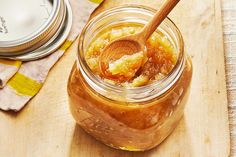 a wooden spoon in a glass jar filled with honey on top of a cutting board