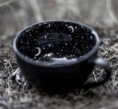 a black cup sitting on top of dry grass covered in drops of water and stars