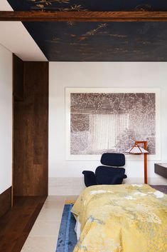 a bedroom with a large painting on the wall and a chair in front of it