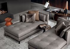 a living room with grey couches and pillows on the floor next to a coffee table